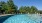 a swimming pool with chairs and umbrellas next to it